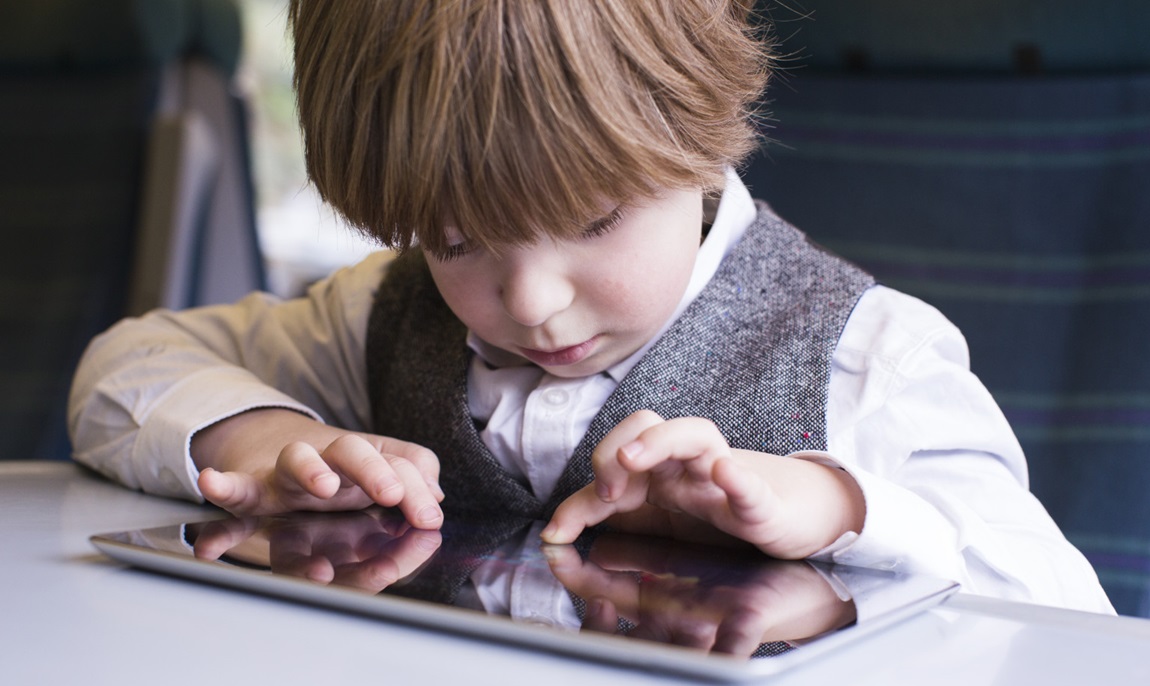 Young boy travels with tablet on train